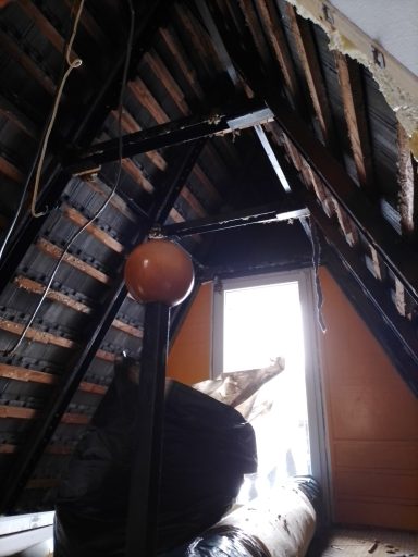 Raum mit schrägen Wänden, einem Fenster und einem runden Objekt in der Mitte.
