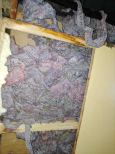 Hier ist eine Decke mit feuchtem, schimmeligem Dämmmaterial und beschädigtem Holzrahmen.