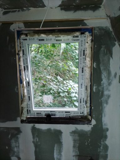Fenster mit unvollständigem Rahmen, Blick auf grüne Pflanzen im Freien.