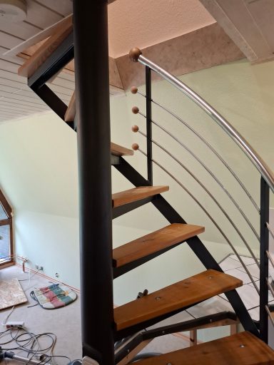 Holztreppe mit Edelstahlgeländer in einem Raum mit unvollendeter Renovierung.