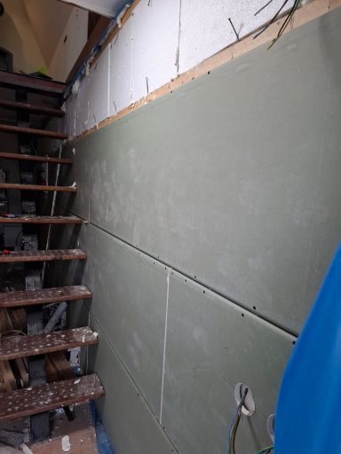 Treppenbereich mit einer grünen Wand und Holzstufen, teilweise im Bauzustand.