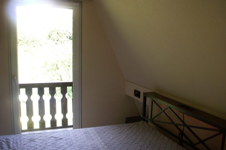 Ein helles Schlafzimmer mit einem Bett und einem Fenster zur Aussicht ins Freie.