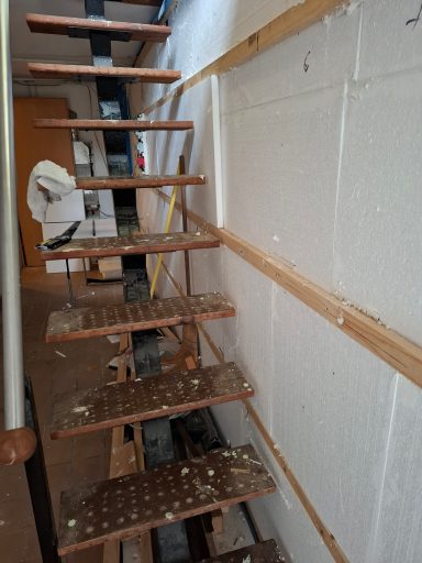 Holztreppe mit sichtbaren Stufen, die an einer Wand entlangführt, im Bauzustand.