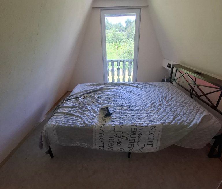 Schlafzimmer1 neu Gemütliches Schlafzimmer mit Bett, Fensterblick ins Grüne und einem Buch auf der Bettdecke.