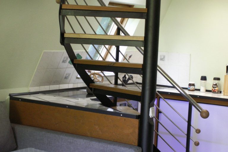 Einfache, geschwungene Treppe aus Metall und Holz in einem Wohnraum mit moderner Ausstattung.