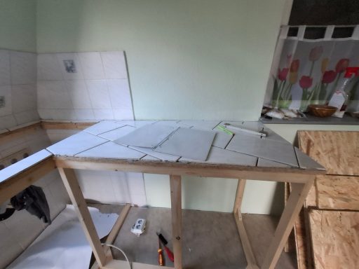 Ein Holzgestell mit Fliesen auf einem Tisch in einem Küchenraum.