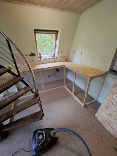 Holzkonstruktion einer Kücheneinheit in einem Raum mit Treppe und Staubsauger.